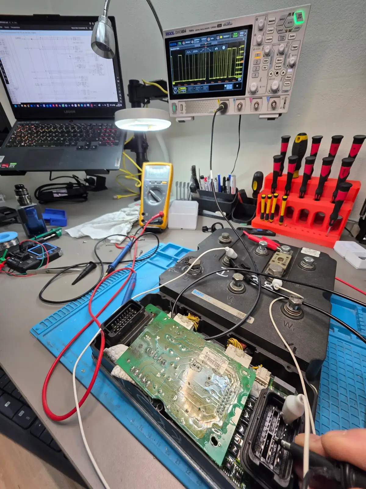 Banco del laboratorio con un controlador abierto, osciloscopio, multímetro y notebook