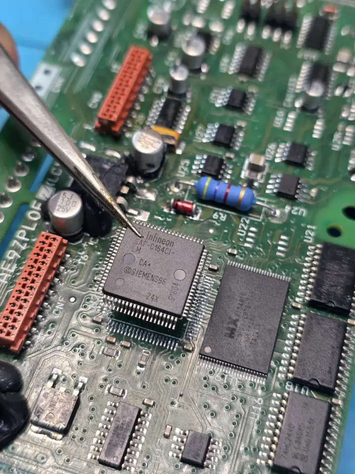 Pinza sujetando un microprocesador sobre la placa de un controlador